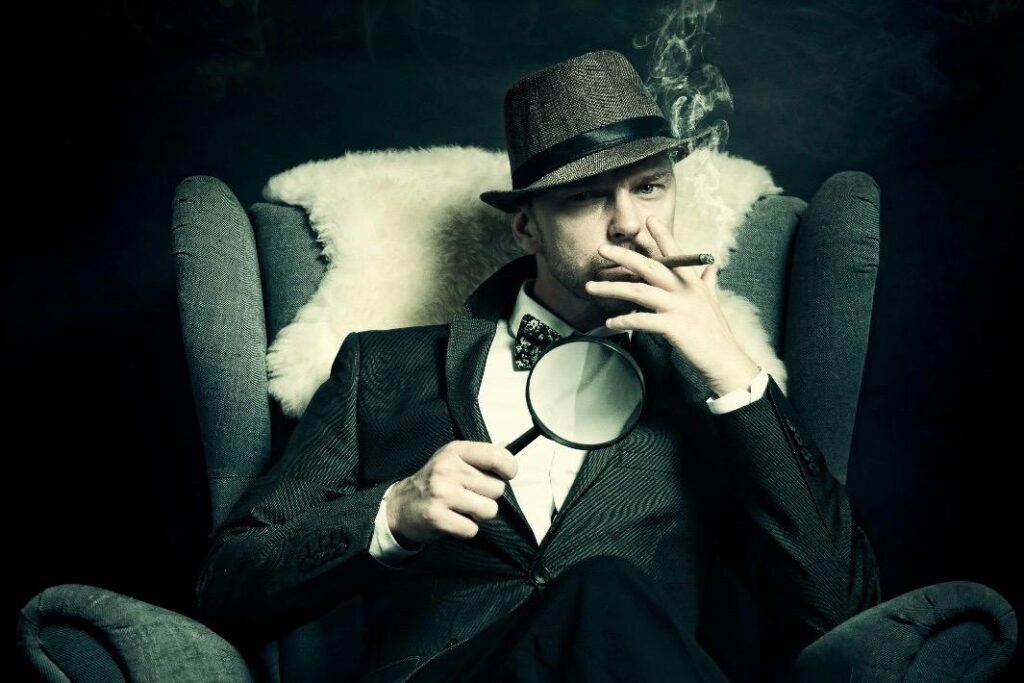 This image shows a man dressed as a detective holding a magnifying glass for a murder mystery party